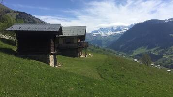 Un chalet doté d’un balcon donnant sur une vallée et des montagnes.