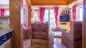 A wooden interior with a kitchen area, a dining table, and a television. - CHALET LA RUIDE - HAUTELUCE LES SAISIES (HAUTELUCE LES SAISIES)