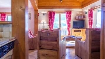 Un intérieur en bois comprenant un coin cuisine, une table à manger et un téléviseur.