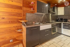 A modern kitchen with wooden paneling, stainless steel appliances, and a tiled floor.
