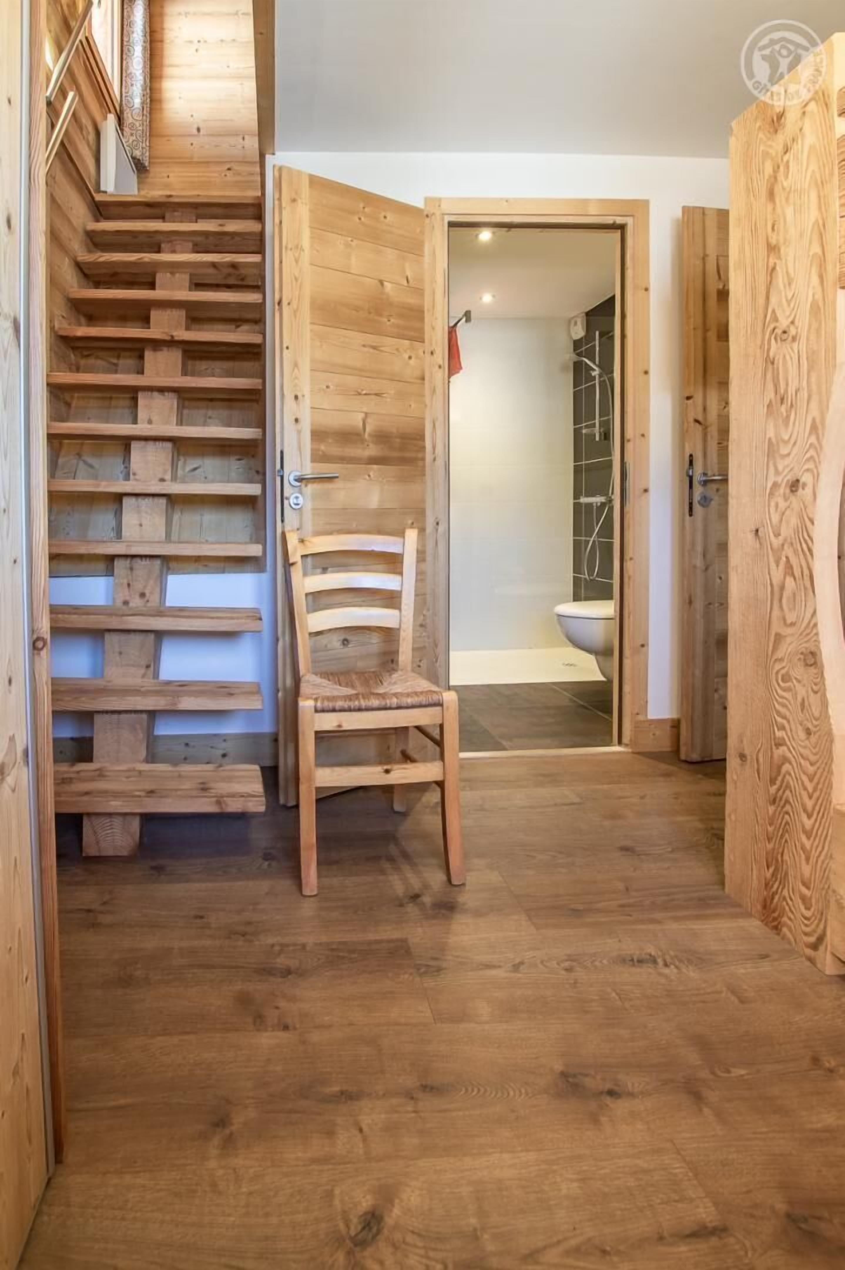 A wooden staircase leading to a bathroom with a shower and toilet.