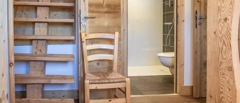 A wooden staircase leading to a bathroom with a shower and toilet.