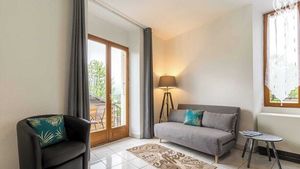 Una sala de estar con sofá, sillón, lámpara y una mesita.