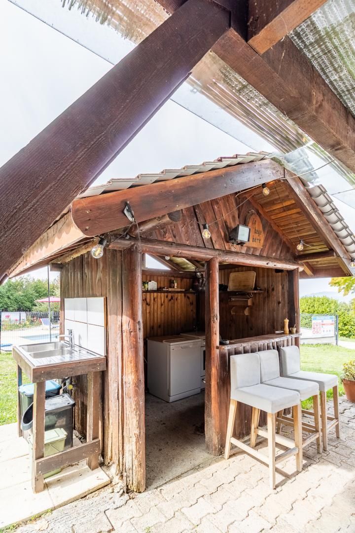 Estructura rústica de madera con barra, asientos y un lavabo.