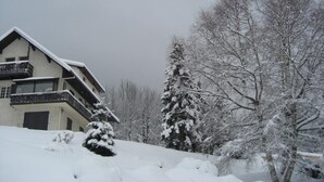 A multi-story building with balconies, surrounded by snow-covered trees and a snowy landscape. - PRE CHARVILLE - LE REVARD (TREVIGNIN)