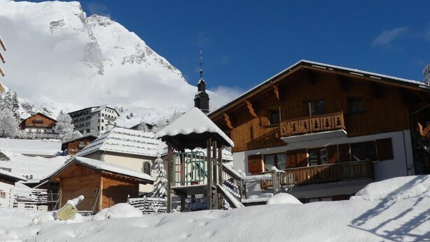 A wooden chalet with a balcony, surrounded by snow-covered buildings and a mountain in the background. - LA CASCADE - LA GIETTAZ (LA GIETTAZ)