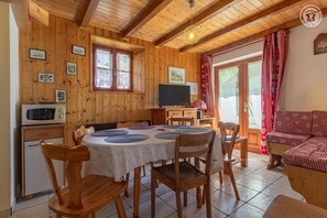 Un interior acogedor de madera con comedor, televisor y sofá.