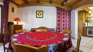 A cozy dining area with a round table covered in a red tablecloth, wooden chairs, and a lamp on a wooden cabinet. - LA CASCADE - LA GIETTAZ (LA GIETTAZ)