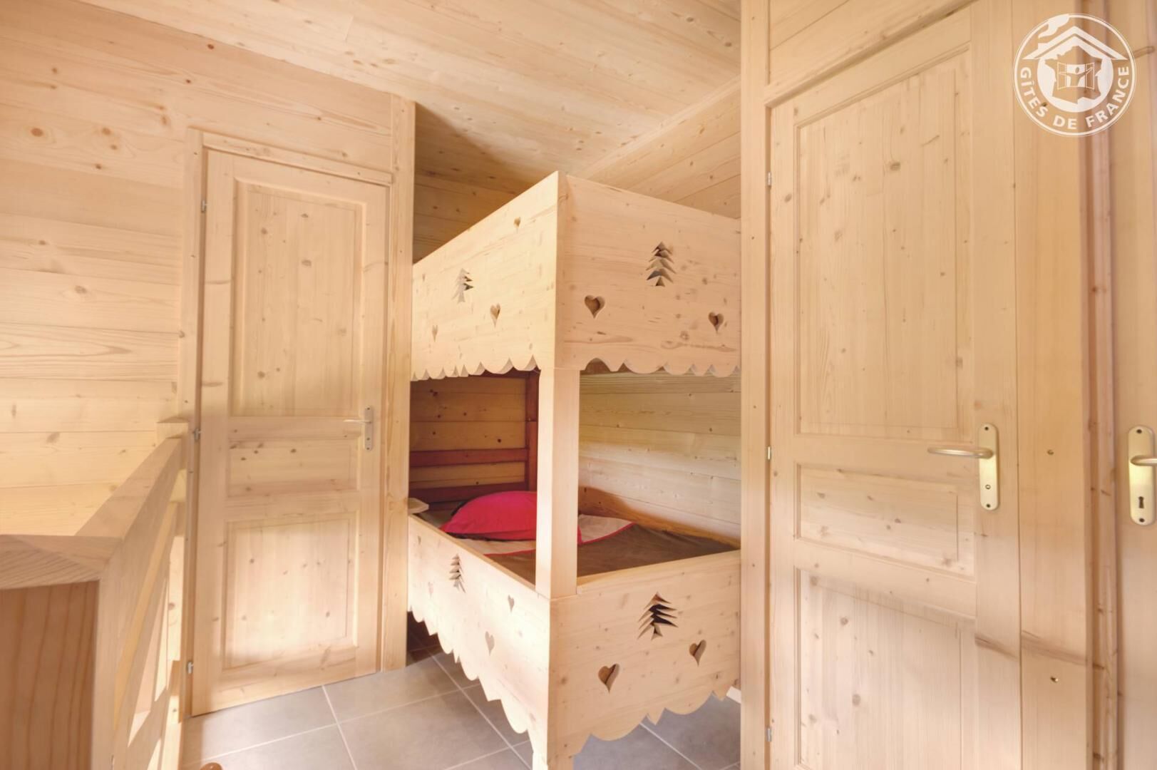 A wooden room with bunk beds, a door, and a tiled floor.
