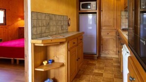 A compact kitchen with wooden cabinets, a microwave, and a refrigerator. - LE REPOSU - BEAUFORT ARECHES (BEAUFORT ARECHES)