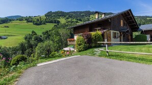 A traditional chalet with a sloped roof, surrounded by lush greenery and a clear view of rolling hills. - LE REPOSU - BEAUFORT ARECHES (BEAUFORT ARECHES)