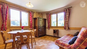 A cozy room with a wooden dining table, chairs, a sofa, and a cabinet. - LE REPOSU - BEAUFORT ARECHES (BEAUFORT ARECHES)