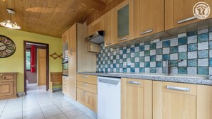 Una cocina con armarios de madera, salpicadero de azulejos y lavavajillas.