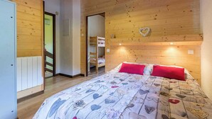 Un dormitorio con techo de madera, una cama con colcha floral y una decoración con forma de corazón en la pared.