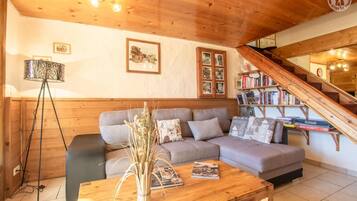 Un salon chaleureux avec un canapé gris, une table basse en bois et une bibliothèque remplie de livres.
