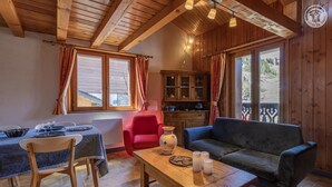 A cozy room with a wooden ceiling, a dining table with chairs, a sofa, and a cabinet with glass doors. - FLORINEIGE - COURCHEVEL (COURCHEVEL)