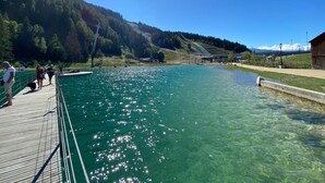 A clear lake with a wooden dock and a small building in the background. - FLORINEIGE - COURCHEVEL (COURCHEVEL)