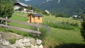 A rural mountain village with traditional houses, a wooden fence, and a stone wall.