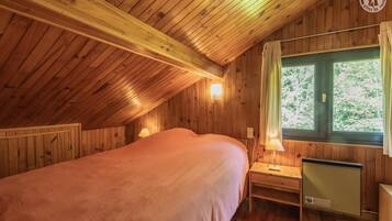 Une chambre confortable située dans les combles, avec un plafond en bois, un lit, deux lampes de chevet, une fenêtre avec des rideaux et un radiateur.