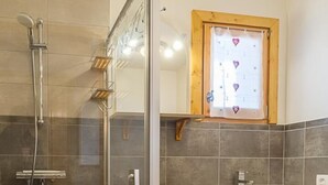 A modern bathroom with a glass-enclosed shower, a wooden vanity, and a small window with heart decorations. - CHALET FIASSE - HAUTELUCE LES SAISIES (HAUTELUCE LES SAISIES)