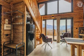 A cozy cabin interior with a wooden interior, a dining area, and a view of mountains. - Trelod - ARITH - Alpine Chalet (ARITH)