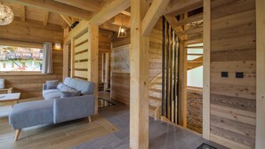 Un interior de madera con sofá, lámpara colgante y ventana con vistas.