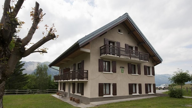 Ein zweistöckiges Gebäude mit einem Balkon im oberen Geschoss, einem Schild, das ein Restaurant anzeigt, und einer Bergblick im Hintergrund.