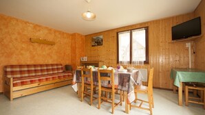 Ein Holzinterieur mit einer Couch, einem Esstisch, Stühlen und einem Fernseher.