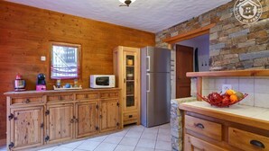 Eine Küche mit Holzschränken, einem Edelstahlkühlschrank, einer Mikrowelle und einer Obstschale auf der Arbeitsfläche.