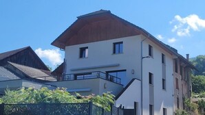 A two-story building with a flat roof, a balcony on the second floor, and a small garden area in front. - L'OREE DU LAC - LES MOLLETTES (LES MOLLETTES)