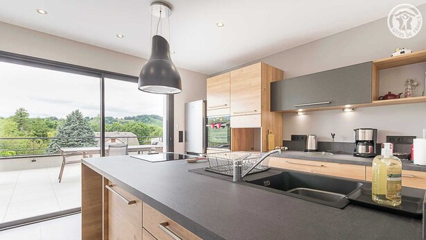 A modern kitchen with a large island, a built-in oven, and a view of the outdoors. - L'OREE DU LAC - LES MOLLETTES (LES MOLLETTES)