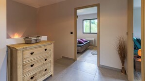A modern bedroom with a wooden dresser, a bed with a view, and a small window. - L'OREE DU LAC - LES MOLLETTES (LES MOLLETTES)