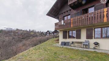 Un bâtiment de style chalet doté d’un balcon, d’un espace extérieur aménagé et offrant une vue sur un paysage montagneux.