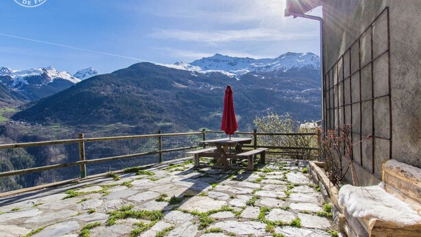 A terrace with stone flooring, a wooden table, and a red umbrella, overlooking snow-capped mountains. - LE MAZOT - VILLAROGER (VILLAROGER)