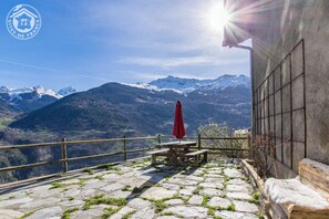 A terrace with stone flooring, a wooden table, and a red umbrella, overlooking snow-capped mountains. - LE MAZOT - VILLAROGER (VILLAROGER)