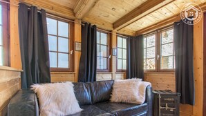 A wooden cabin interior with a leather sofa, black curtains, and a metal safe. - LE MAZOT - VILLAROGER (VILLAROGER)
