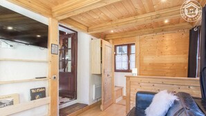 A wooden interior with a sofa, a television, and a door leading to another room. - LE MAZOT - VILLAROGER (VILLAROGER)