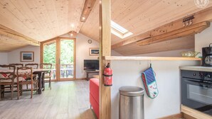Una cocina acogedora con vigas de madera, un comedor con mesa y sillas, y un ventanal grande.