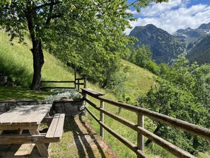 A picnic table and wooden railing overlooking a mountainous landscape.