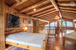 Une cabane en bois avec une chambre à coucher située en mezzanine, un coin repas et une vue sur les montagnes.