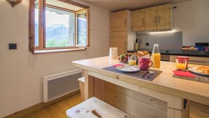 Eine Küche mit Holzausstattung, einem Fenster mit Aussicht, Frühstücksgebäck auf der Arbeitsfläche und einem kleinen Hocker.