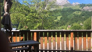 En träveranda med picknickbord och utsikt över ett bergigt landskap.