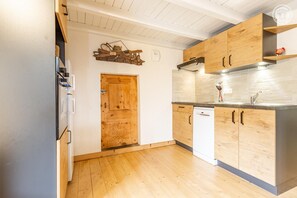 Une cuisine avec des meubles de rangement en bois, un lave-vaisselle blanc et une porte en bois.