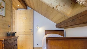 Una habitación de madera con una cama, un tocador y una puerta.