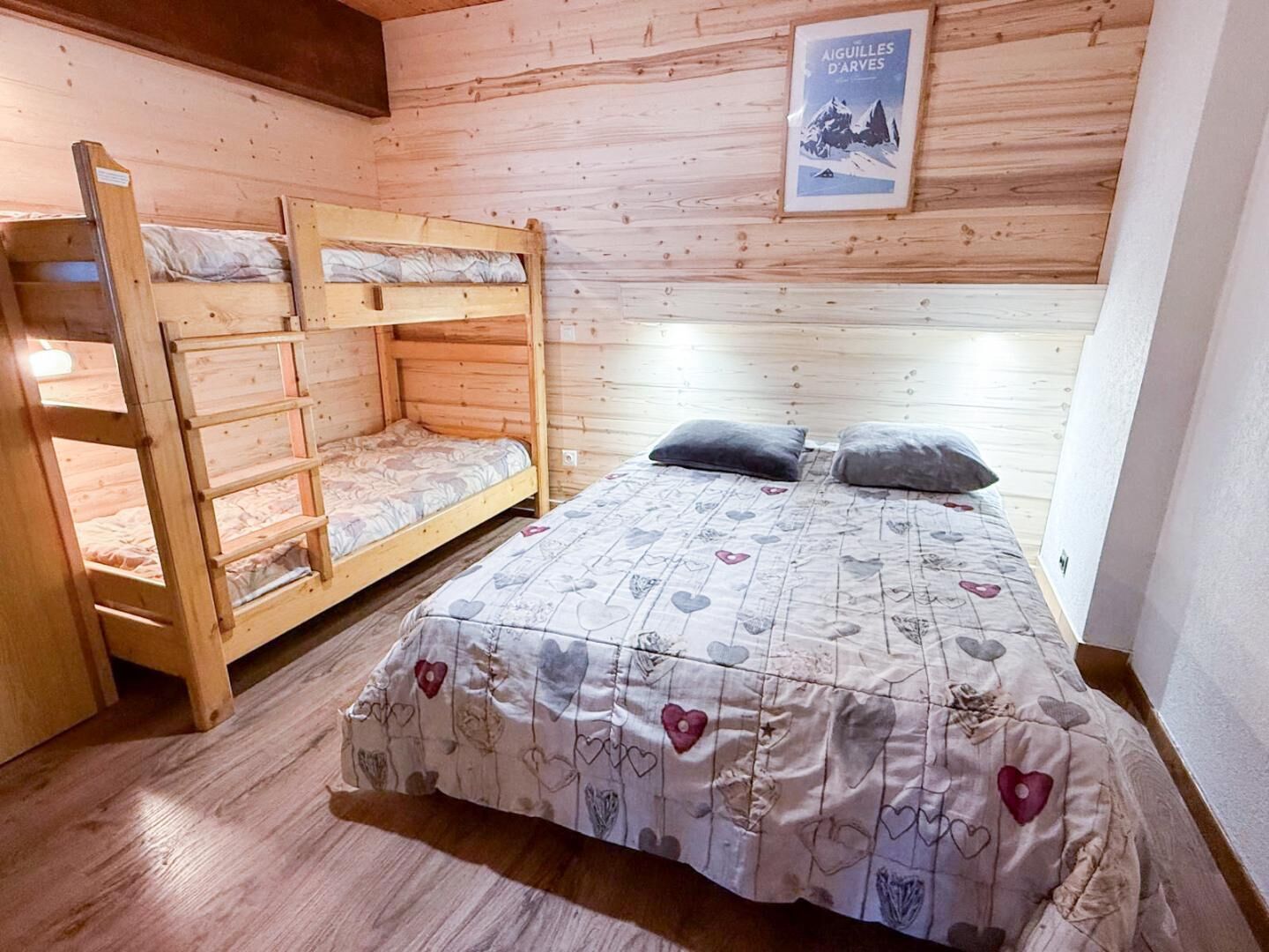 Una stanza con un letto a castello di legno, un letto singolo e un poster appeso al muro.