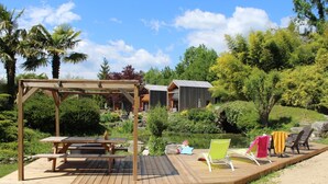 Eine Holzterrasse mit einer Pergola, einem Picknicktisch und Liegestühlen.