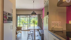 Eine moderne Küche mit Essbereich, einem großen Fenster und Blick auf Grünfläche.