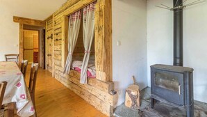 A rustic wooden room with a bed, a dining table, and a wood-burning stove. - LA VARNIERE - BEAUFORT ARECHES (BEAUFORT ARECHES)
