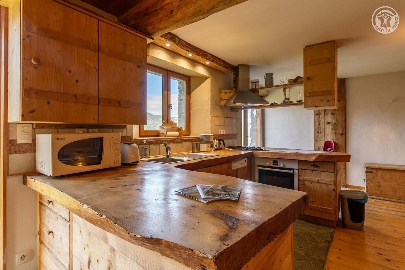 A rustic kitchen with wooden cabinets, a built-in microwave, a sink, and a stove.