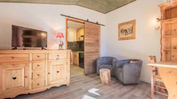 Une pièce confortable avec un meuble en bois, une télévision, une lampe rouge et un coin salon comprenant une table et des chaises.